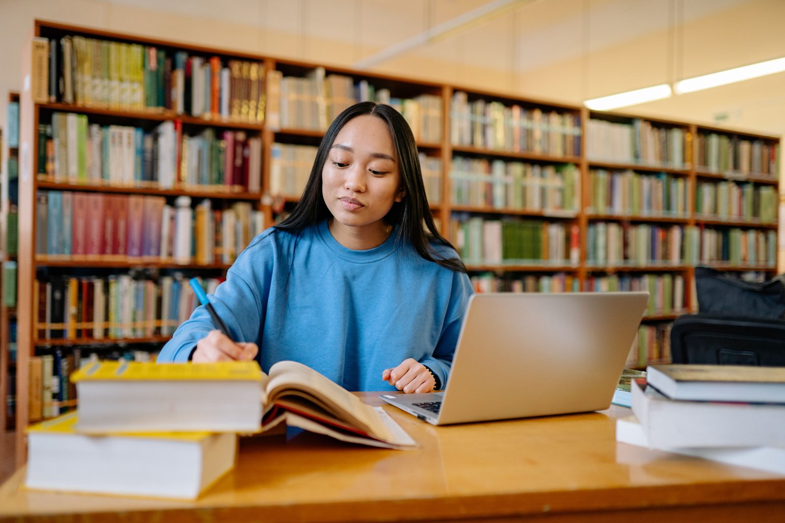 A student working on coursework at a laptop with notes and books around them