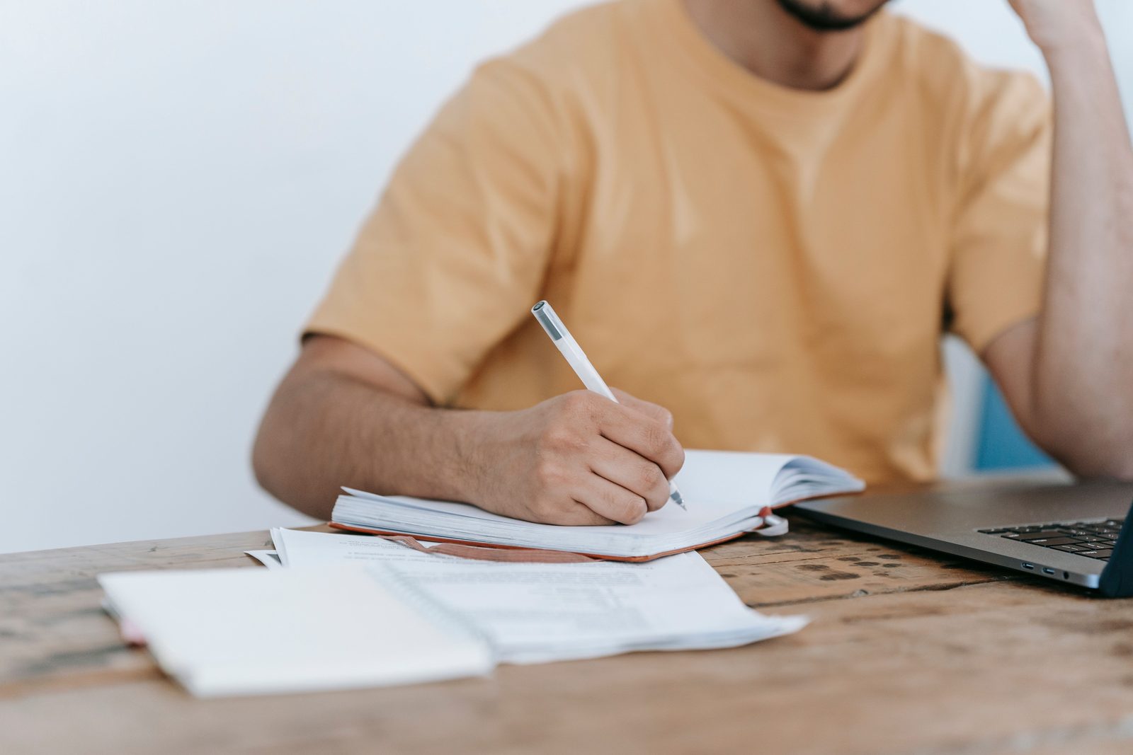 A student writing in an exam hall with papers and no devices