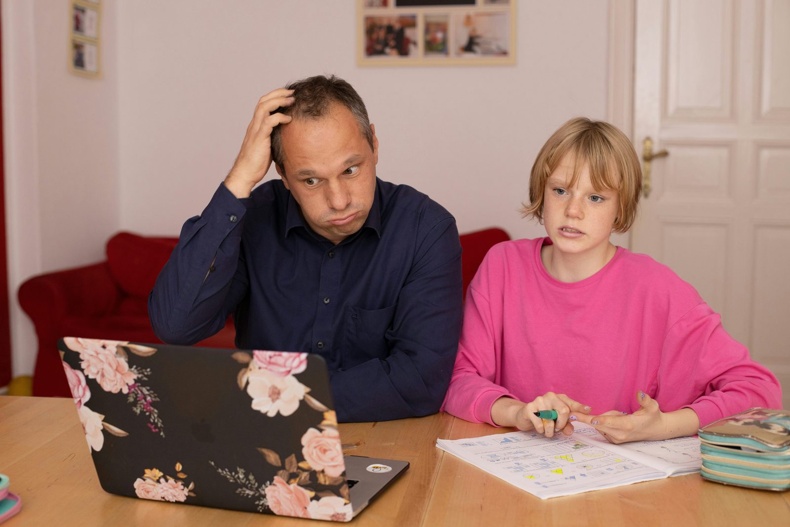 A parent and child talking together over homework at a table, screen closed